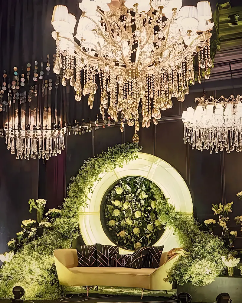 Chandelier above a green floral ring and gold sofa
