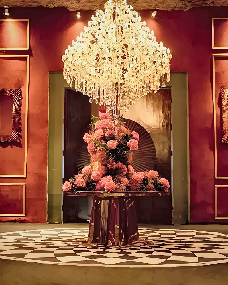 Crystal chandelier above a pink floral centrepiece in a red-panelled room
