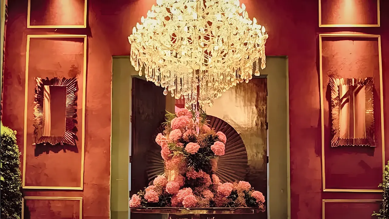 Crystal chandelier above a pink floral centrepiece in a red-panelled room