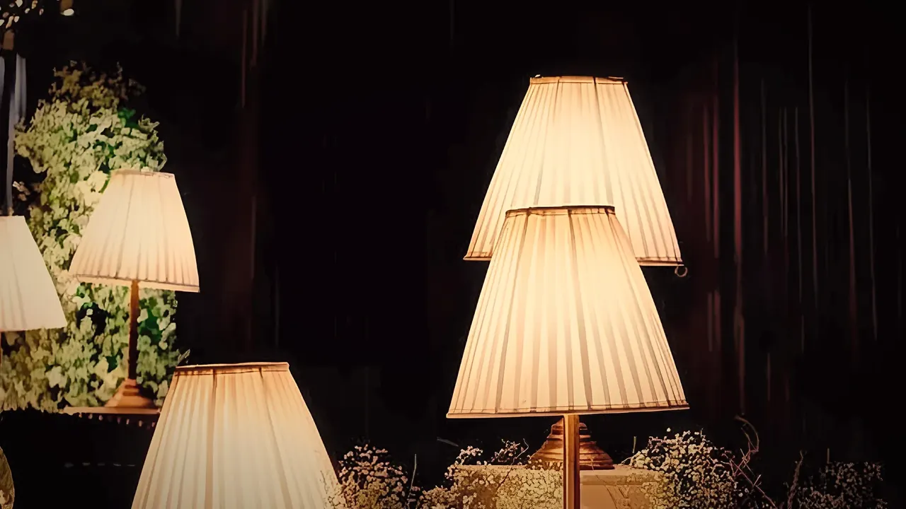 Pleated lamps glowing warmly in a candle-lit garden reception after dark